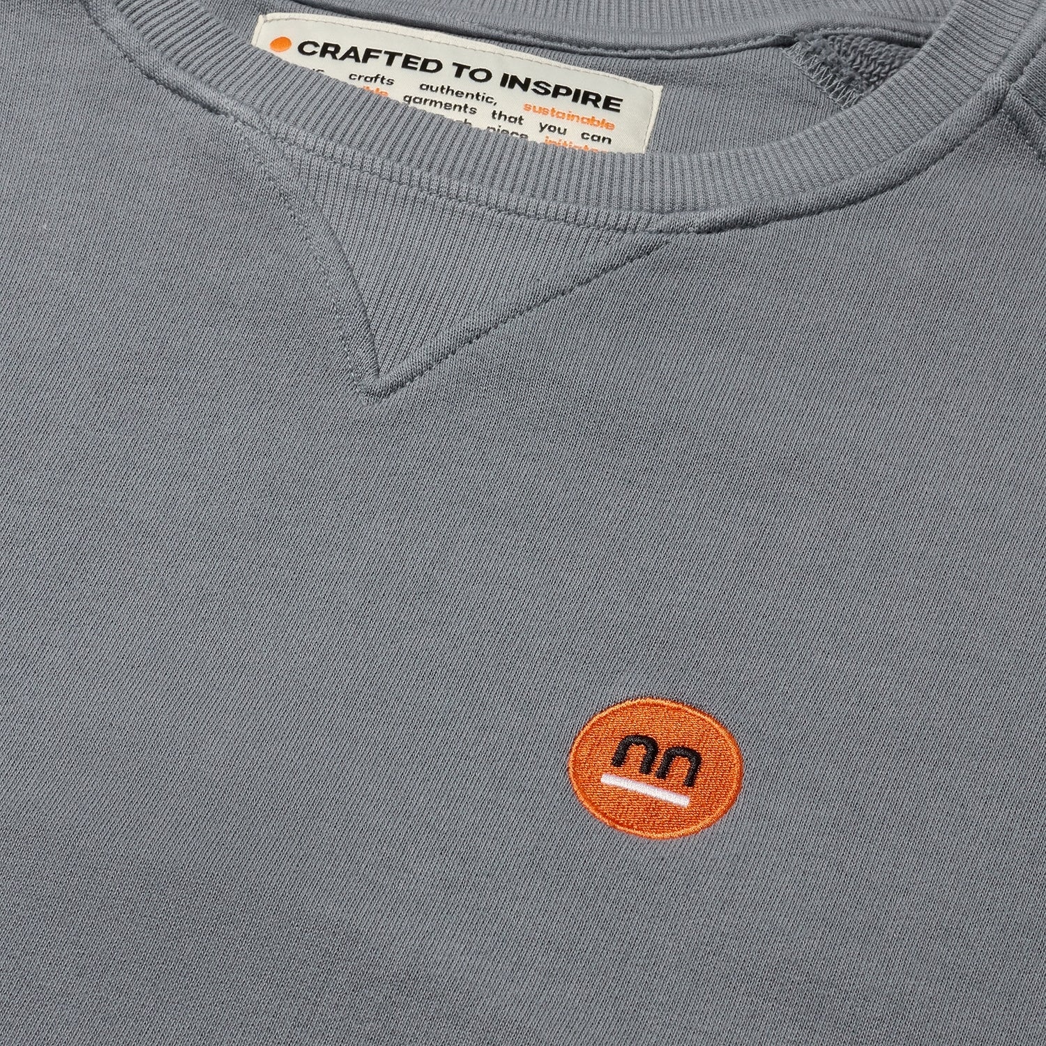 Close-up of grey sweatshirt's neckline showing small Pamuuc label.